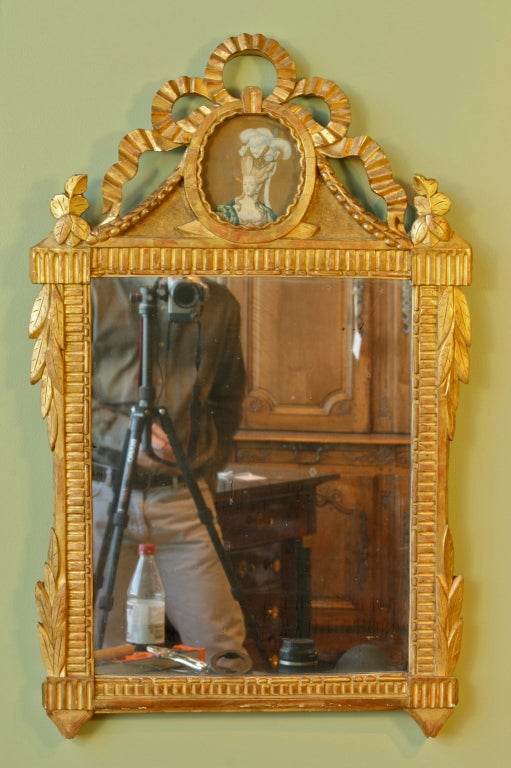 A charming French giltwood trumeau mirror with inset portrait of Marie Antoinette (period Louis XVI, circa 1790). The trumeau has a nicely-carved ribbon cartouche with laurel swags, and its original mercury glass.