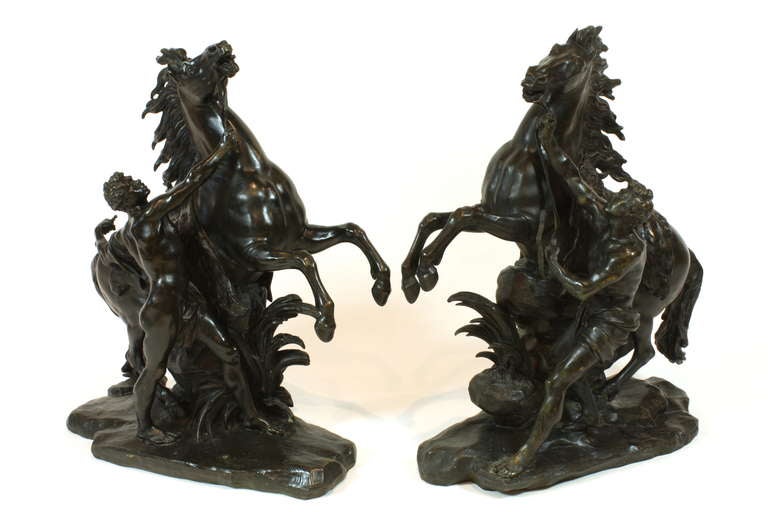 Pair of 19th century French patinated bronze sculptures of the Marly horses. These two sculptures were modeled after the large marble sculptures representing wild horses restrained by grooms, commissioned in 1739 by King Louis XV from the sculptor,