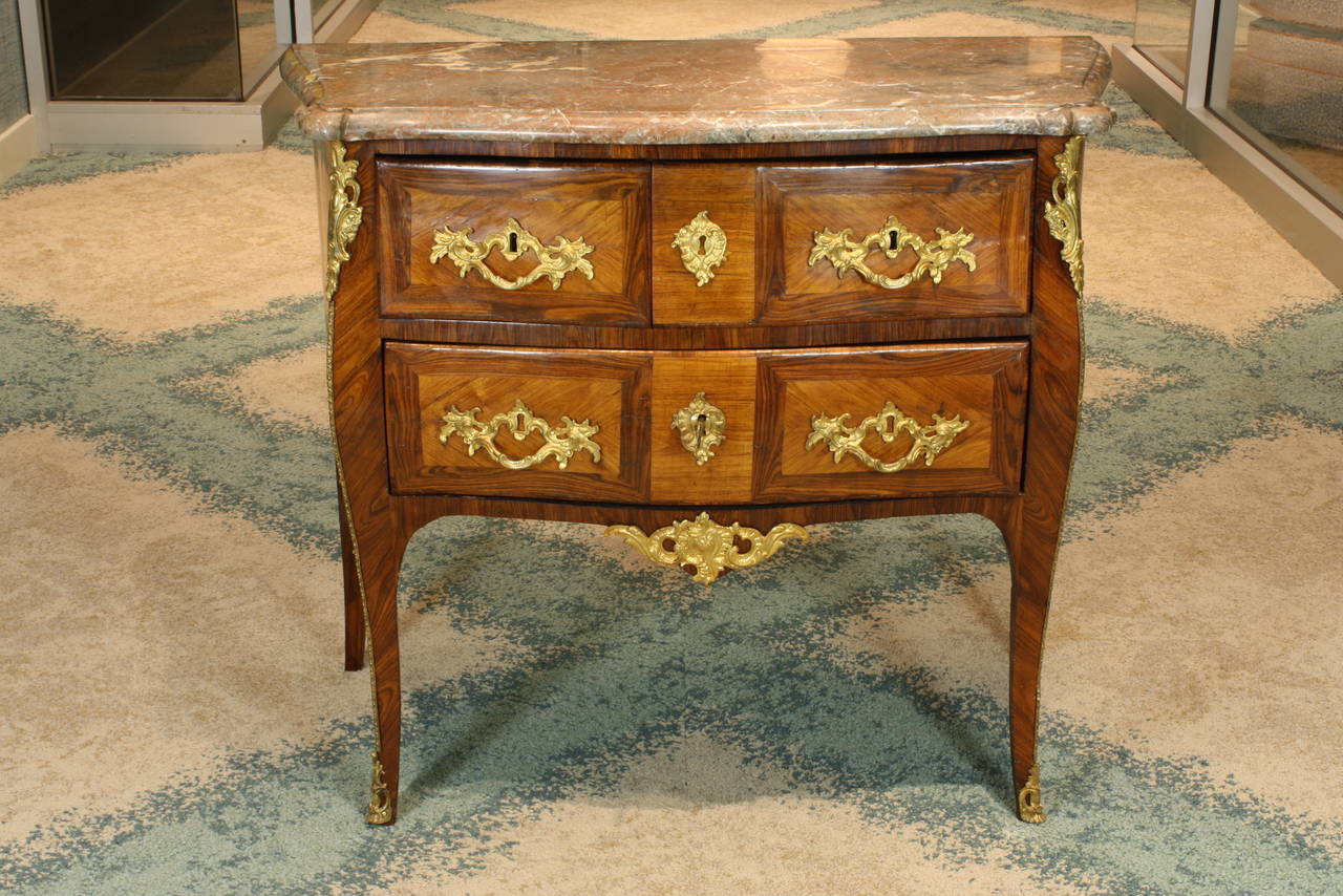 French Louis XV period commode, with gilt-bronze mounts and feet, and rouge royale marble top (Circa 1750).  The case features tulipwood (