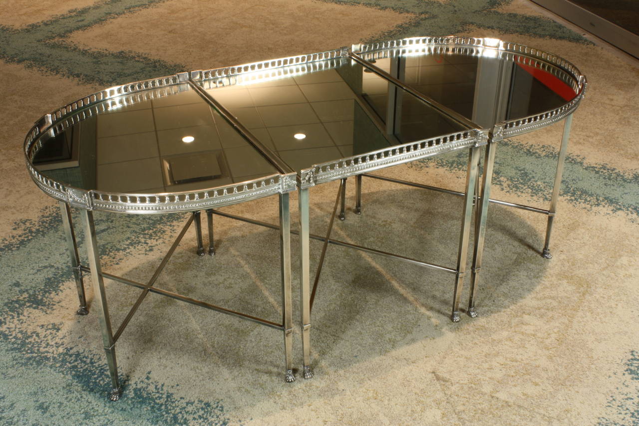 French neoclassical silvered-bronze three-piece coffee table, in oval form, with detailed, pierced gallery, stretchers and paw feet.