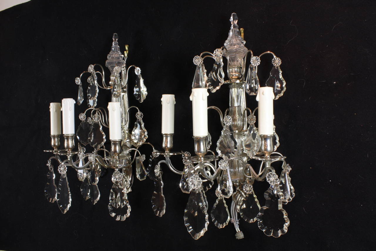 Pair of nice quality French, Louis XVI style silvered-bronze and crystal sconces with three arms.  The sconces have a crystal column back, and are decorated with a variety of cut crystal pendalogues and surmounted by a spear.  The silvered-bronze