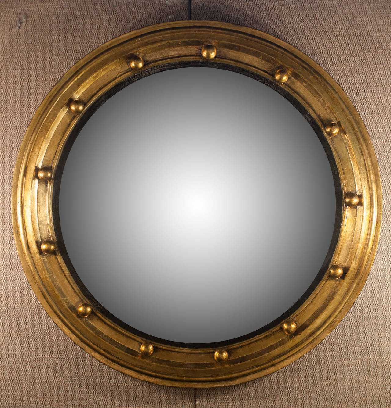 Round gilt wood Regency style Bullseye mirror with convex glass set into a molded slip. The classic gilt orbs for this style of mirror are found around the perimeter.