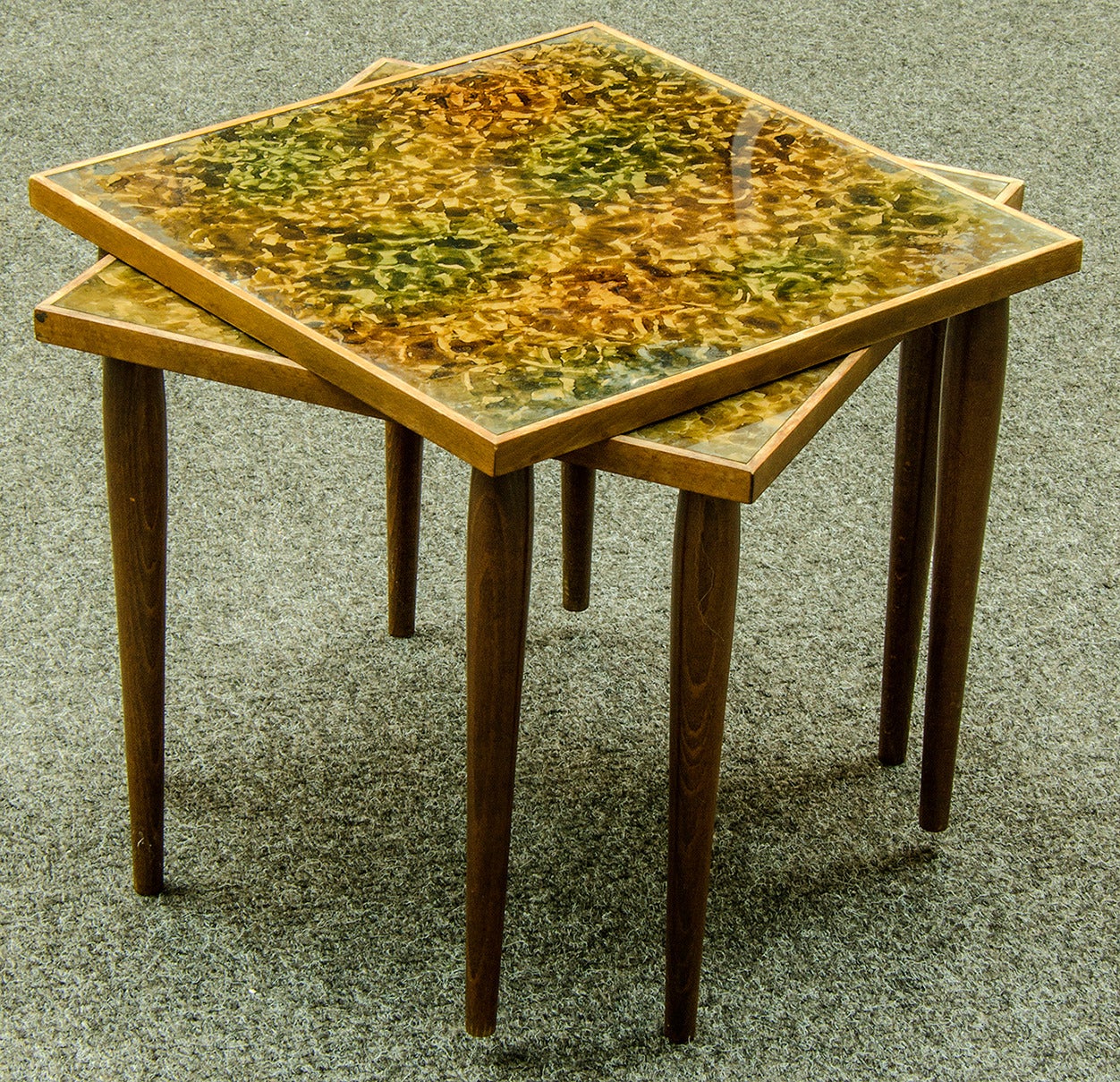 Pair of 1950s Danish modern stacking tables. The frame and legs are walnut and the top is a reverse painted tortoise pattern on glass.