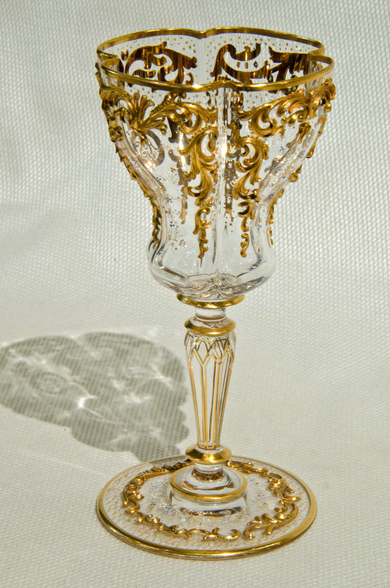 Set of 8 perfectly rare Moser wine goblets.  Hand blown with a quatrefoil shaped bowl.  Heavily applied gold decoration is applied to the bowl and foot.  The faceted stem is outlined in gold.  Each piece has a crest and monogram.