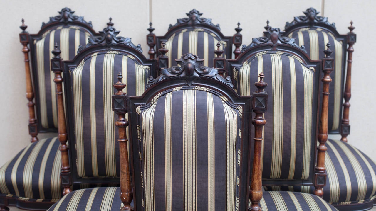 Set of six matched Renaissance Revival Victorian side chairs. The frames are hand-carved walnut. The side back supports and legs are turned. They have been upholstered in a striped fabric.
