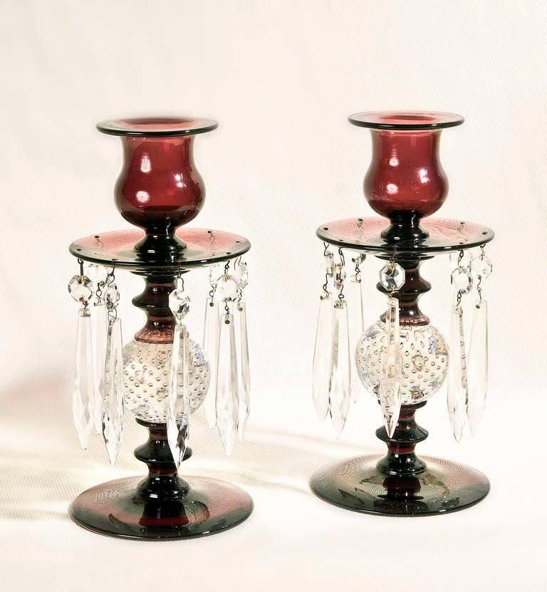 Pair of amethyst glass Pairpoint candlesticks.  Each piece has eight dangling crystal drops from its bobeche and supported by the Pairpoint trademark uniform bubble design.  The bottom is finished with a polished pontil.