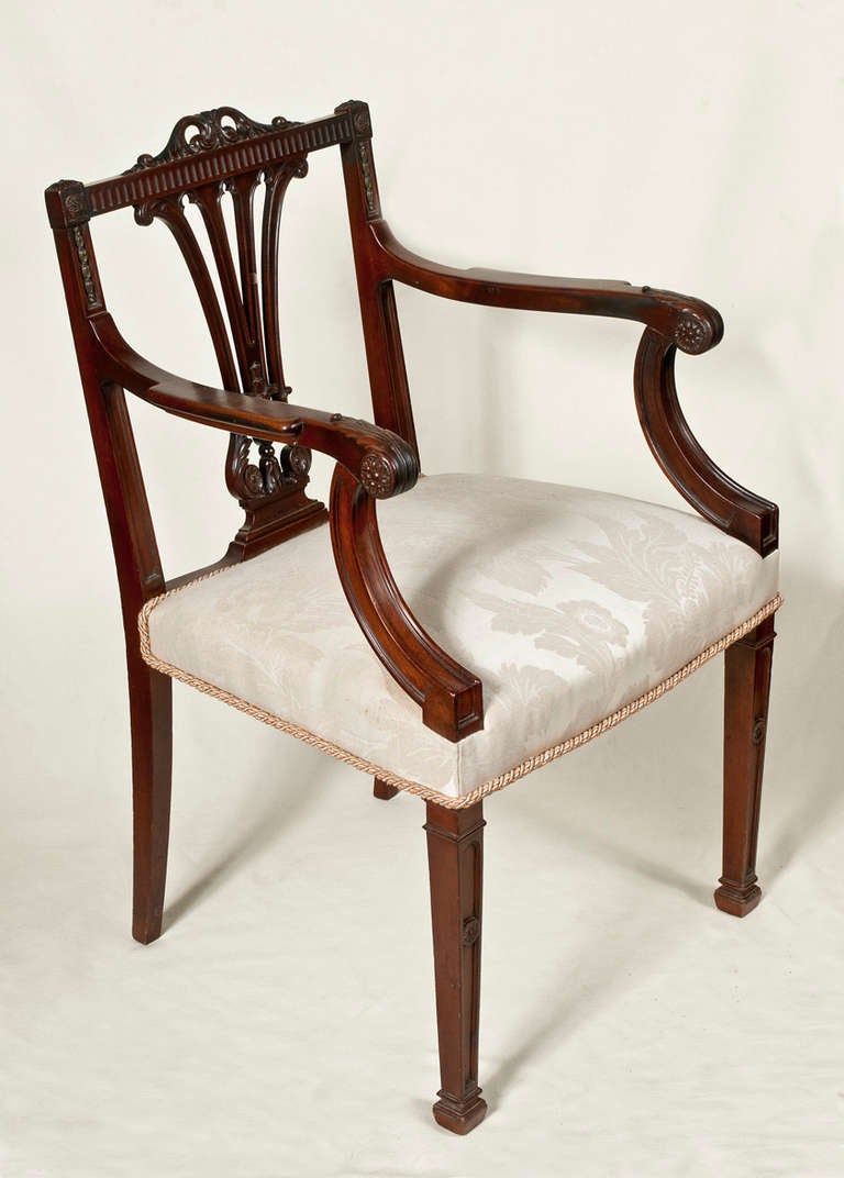 Set of eight Georgian style dining chairs including 2 armchairs and six side chairs.  Solid mahogany with gilt brass bellflowers starting on each side of each chair at the crest rail trailing down to the arm.  The six side chairs are upholstered in