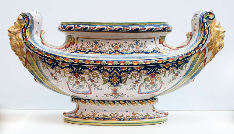 Monumental French faience jardinière decorated in painstaking detail. The handles are decorated with faces in an ochre yellow tone. Henri Delcourt's  factory La Madeleine was in Boulogne-sur-Mer. Signed on the underside.