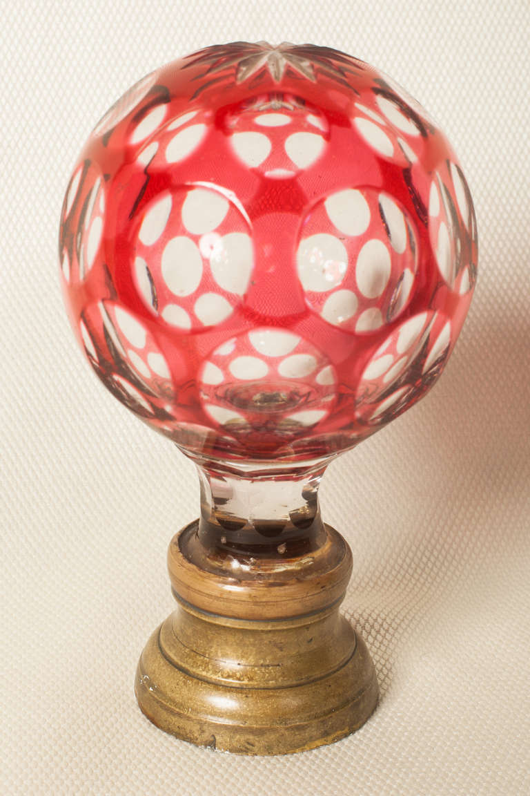 St. Louis boule d'escalier [newel post finial] in cranberry overlay on clear glass and cut back into a lens pattern and star cut on top.  The ferrule is bronze as is the original screw plate on the bottom.