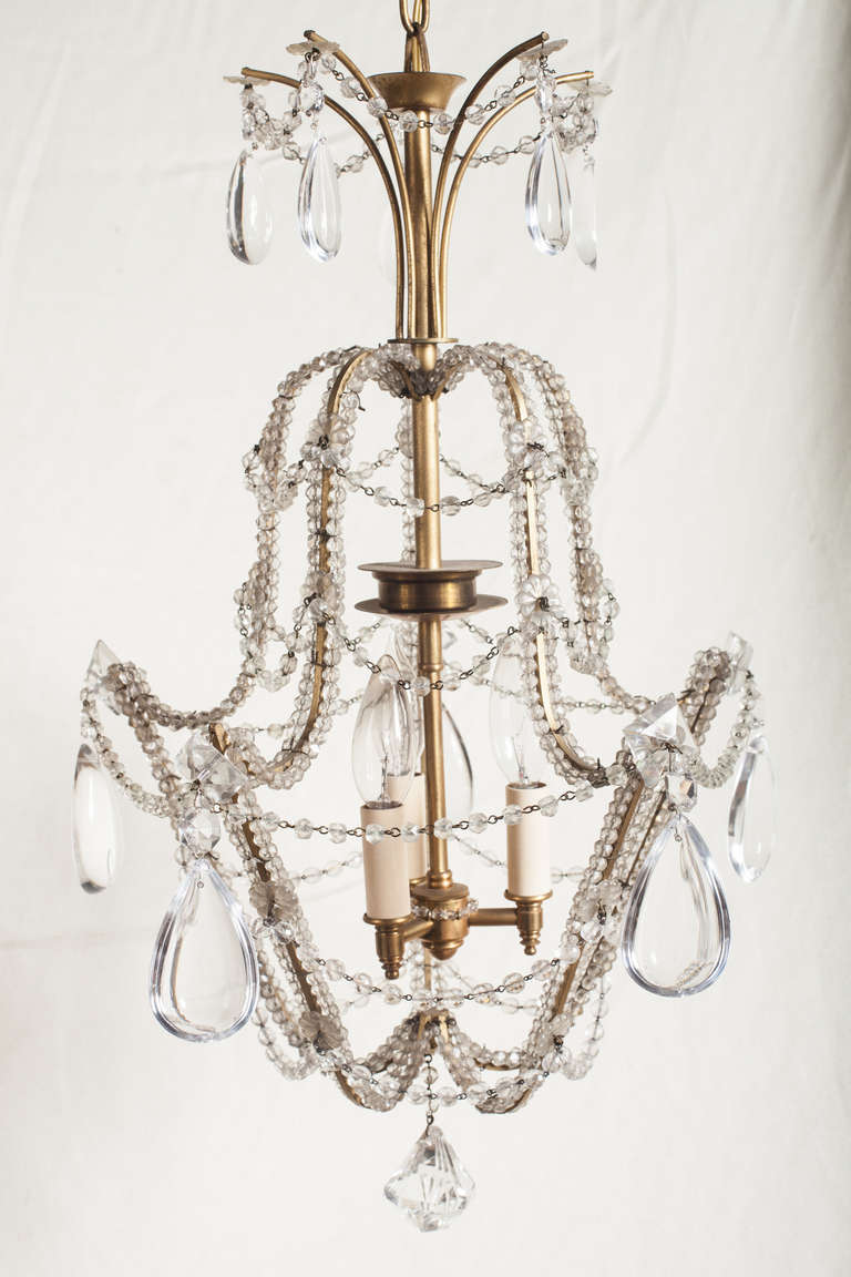 Small three light chandelier with beaded arms and swags.  The crystals are smooth rounded teardrops that are flat on the back.