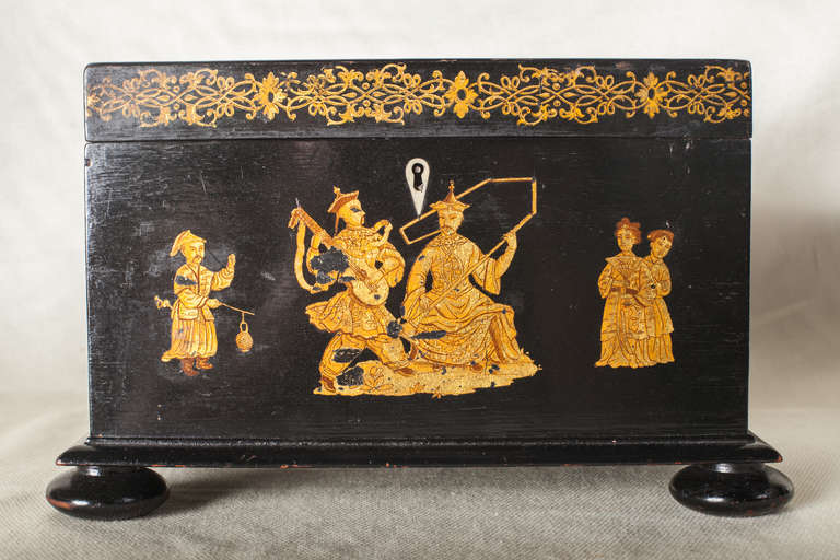 Large decoupaged black tea caddy with a  chinoiserie motif.  The box rests on four squashed bun feet.  The interior has much of its silvering intact.