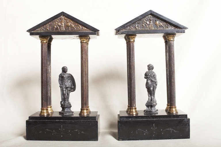 Pair of neoclassical Grand Tour temples in Belgian Black marble and bronze. Each temple has a figure, one male and one female. The front of the triangular pediment has a battle scene in relief. The marble base has stylized carving.
