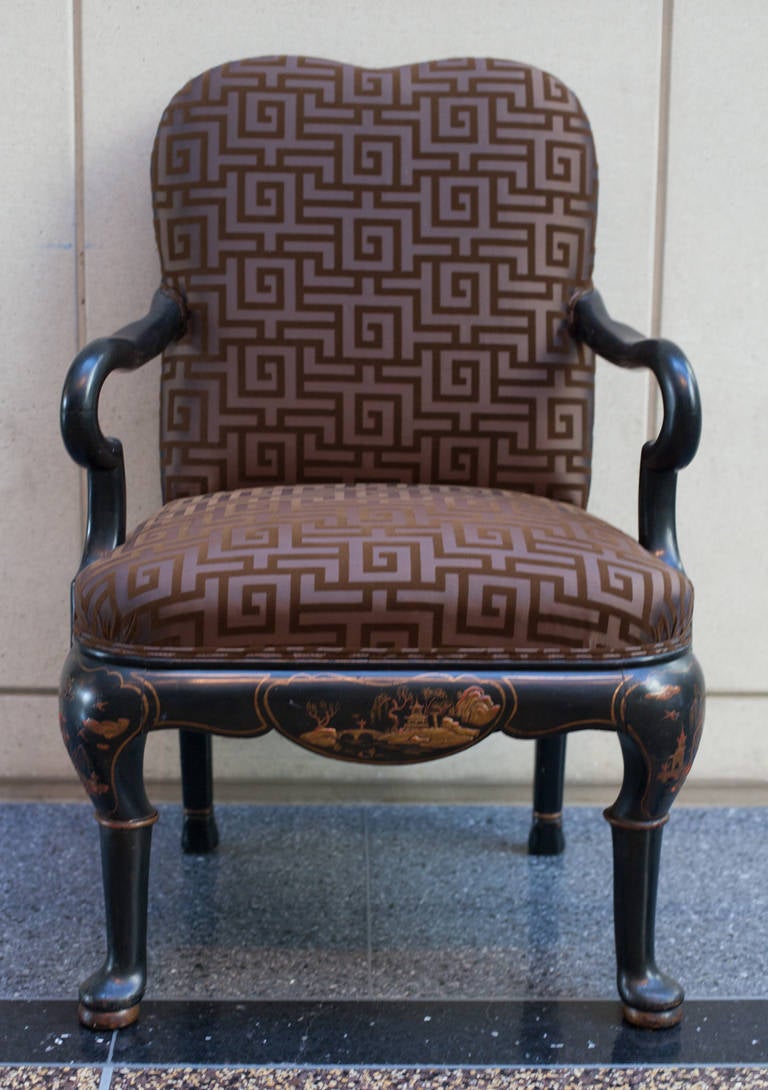 Georgian style japanned armchair.  Graceful formed frame in black with chinoiserie decoration in reds and golds.  The frame is outlined with a thin gold line.  Upholstery is in a greek key pattern.