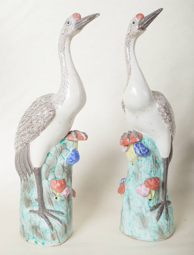 Pair nineteenth century porcelain Cranes.  The birds are in shades of white and grey.  The feathered backs are beautifully decorated.  They are standing amongst flowering vegetation.  The bases are marked with a chop type seal.