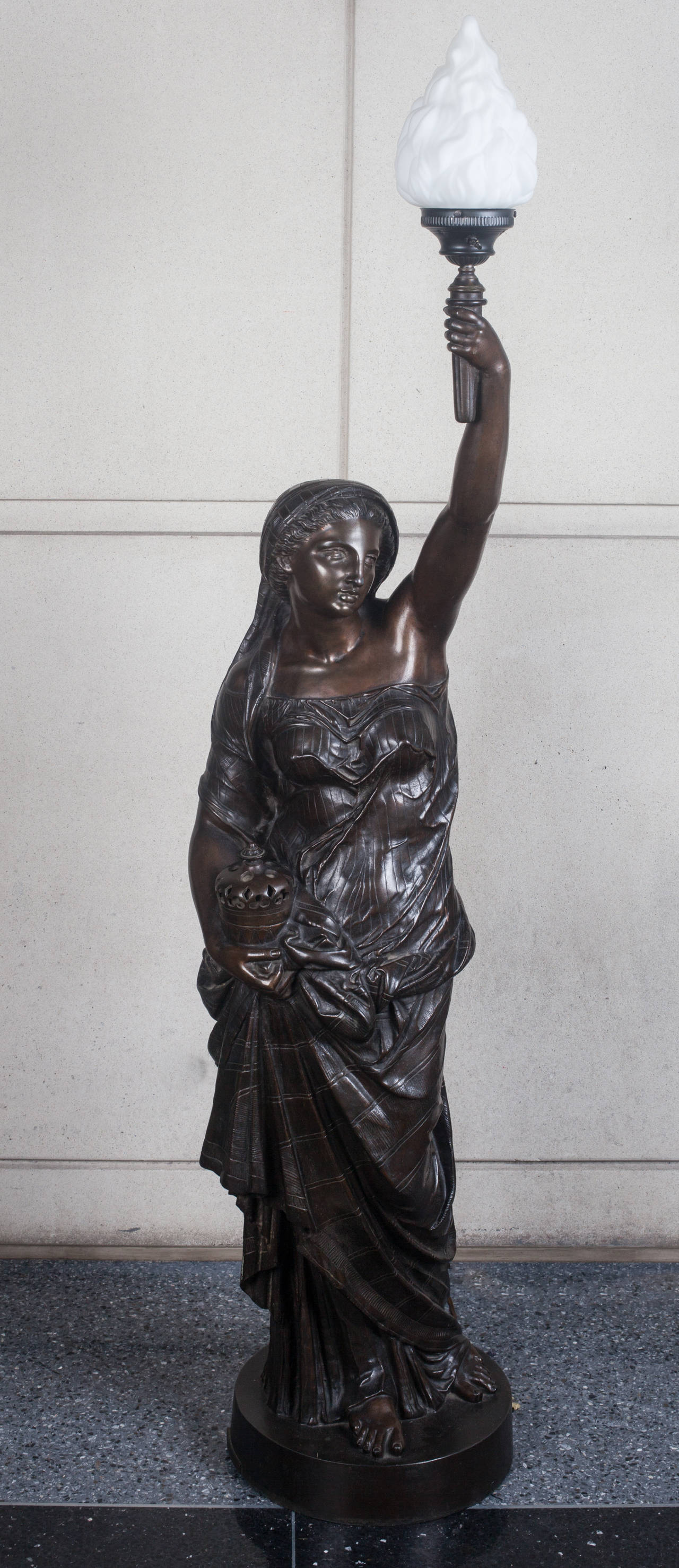 This tall classically draped female figure holding a torch probably stood upon a newel post in a great hall.  She stands on a circular plinth with a makers plaque  marked Miroy Freres-Paris.  These newel post lights of this large size are very