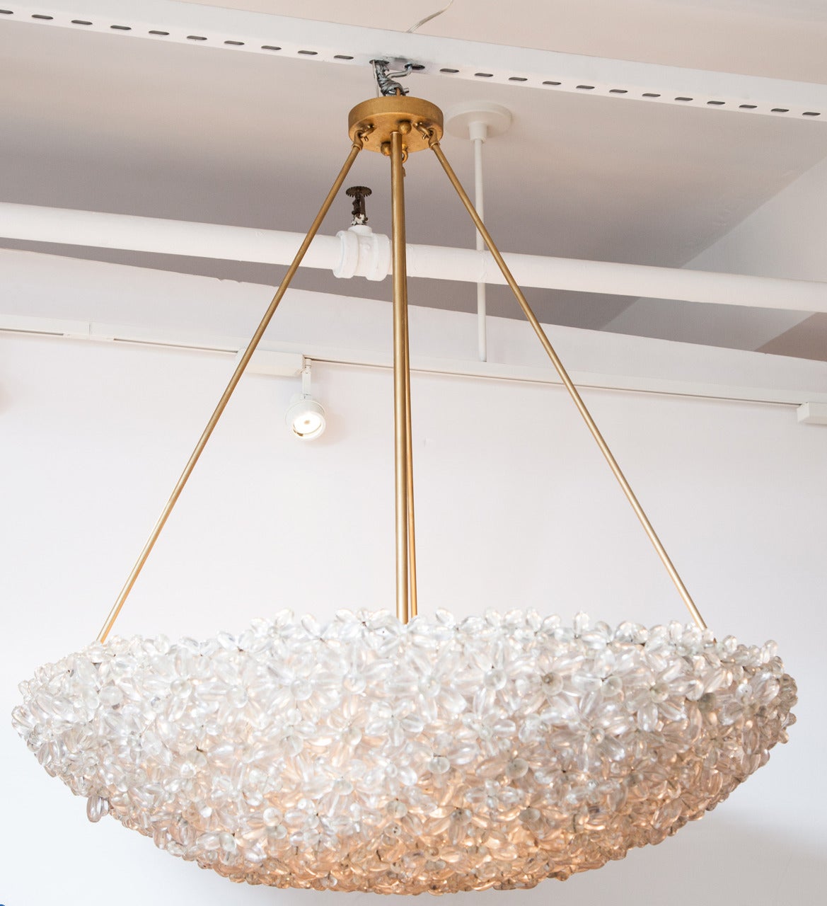 This stunning piece is made up of Lucite daisies that are joined together, creating a lovely half-moon bouquet with light passing through it. This unique piece is hung from three brass rods and can be a focal point for any room.