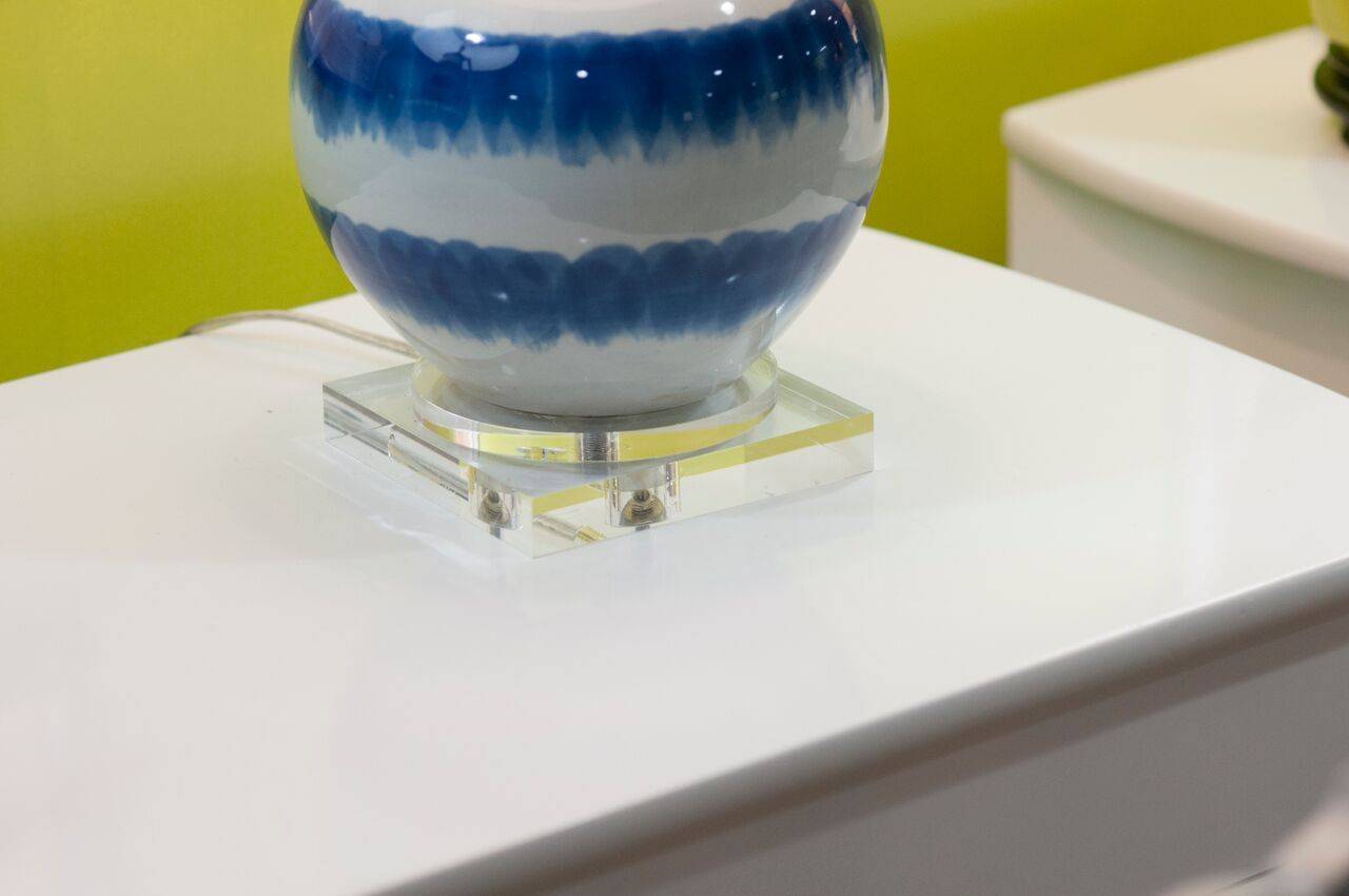 A pair of ceramic lamps with a wavy stripe pattern on Lucite base. A modern twist on Classic blue and white, this duo will freshen up any room.
