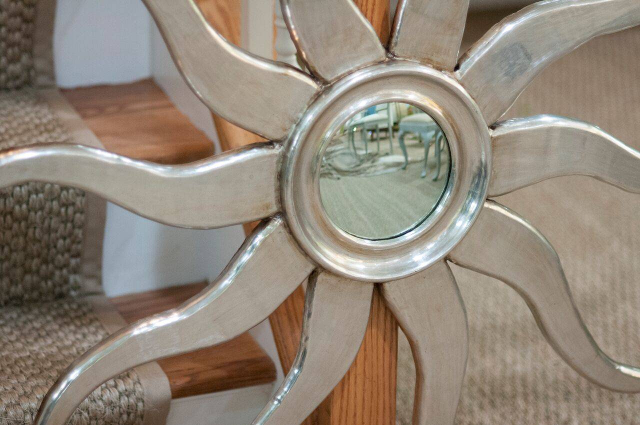 A whimsical, sunburst mirror in silvered wood with wavy rays and a molded centre.