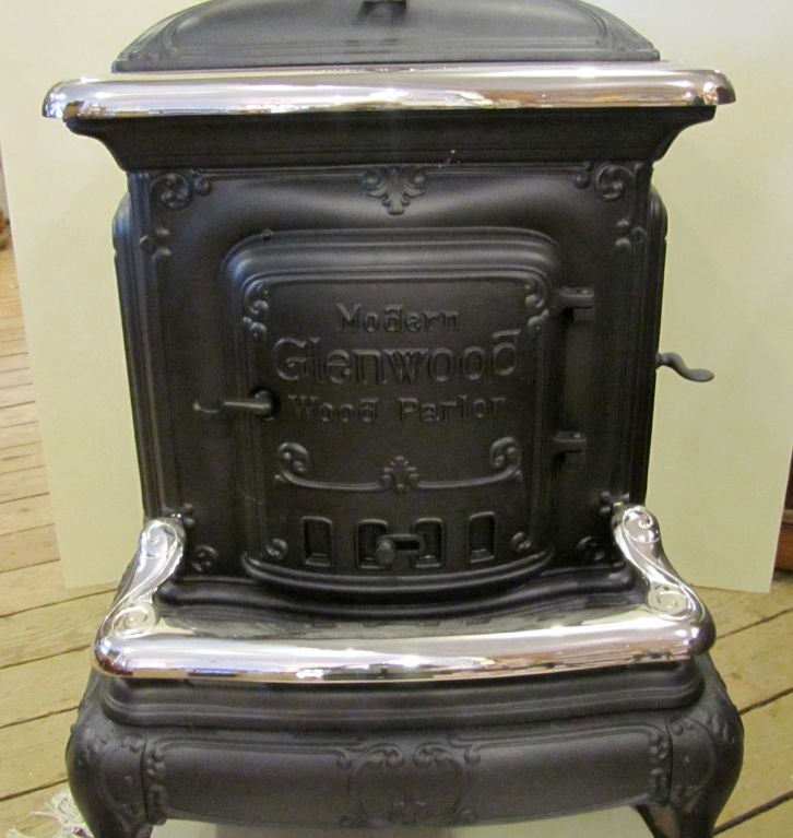 Antique Glenwood parlor stove - cast iron with fancy finial top with front and side loading doors.
