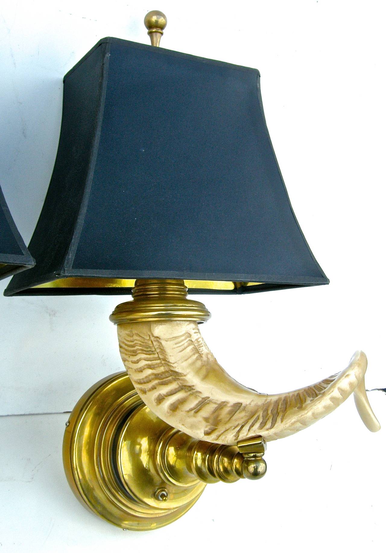 An elegant pair of vintage, Chapman Lighting Company, wall lights. Having striking faux-horn motifs with beautiful brass-turned bases. Gold lined black shades and original ball mounted finials. H below to top of finial.