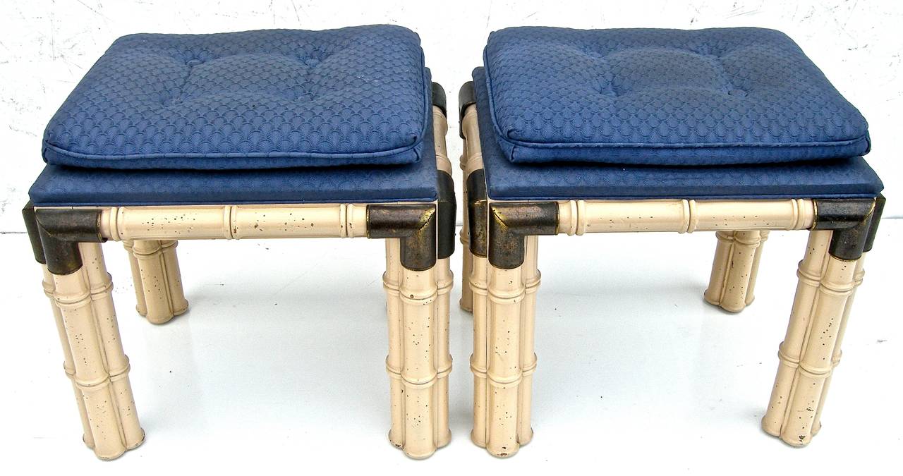 Extremely handsome pair of vintage, wooden, faux-bamboo stools attributed to Maison Jansen. Striking brass corner adornments with attached cushions in original fabric on bold, cluster-style bamboo legs.
