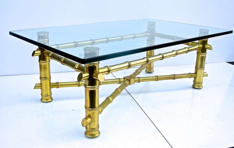 Striking vintage, faux bamboo and gilt coffee table. Having a thick wooden. bamboo style, gilt painted base with heavy glass top creating a high style standout. Subtly elegant. Glass Measurements: H-.75