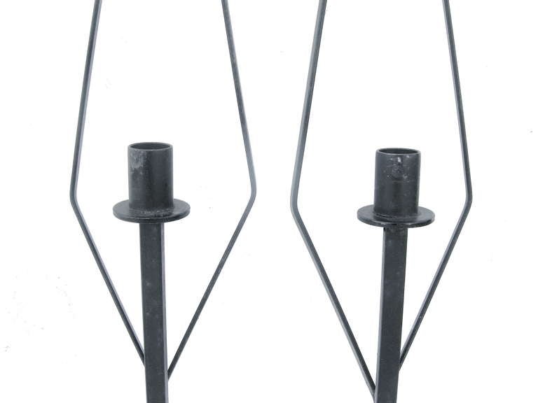 An aesthetically simple yet graphically appealing pair of striking black, hand wrought-iron candle sconces in the style of Paul McCobb. Having bold angular shapes and forms.
