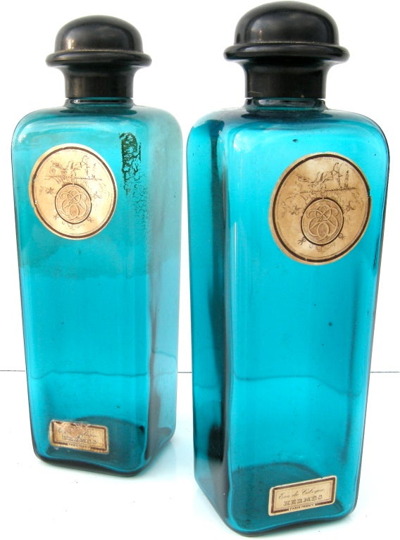 A beautiful pair of vintage Hermes Cologne bottles.  Encased in eye catching aqua/turquoise blue glass with bold bakelite caps. High style grooming from days gone by.