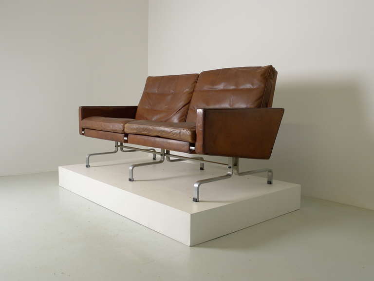 Poul Kjaerholm for E Kold Christensen , Denmark , 1958 . A PK 31/2 two seater sofa in original cognac leather , plated steel frame with the EKC stamp to the underside . Down filled leather cushions .
The leather is original and has areas of