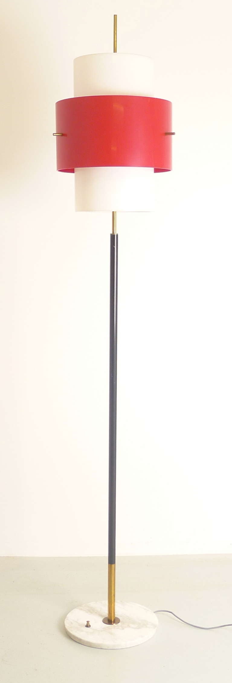 Stilnovo floor lamp , Italian, 1960s , marble base incorporating foot switch , brass and black enameled central pole supporting inner shade of white perspex and outer in red. Shades conceal three bulb holders to which there is an applied yellow