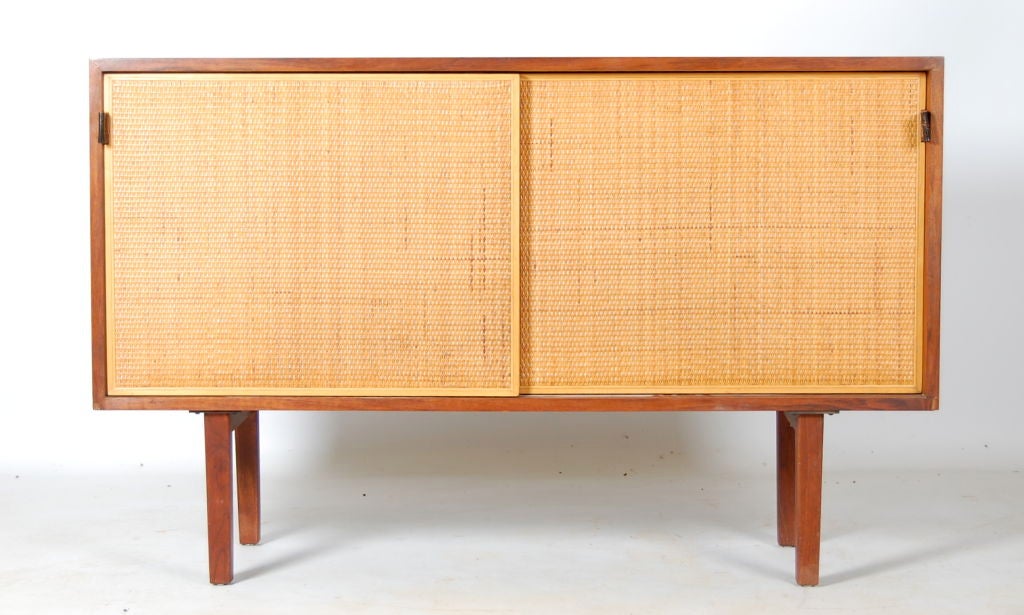Florence Knoll cane fronted credenza with stunningly grained walnut case and two sliding doors with leather pulls . Right side opens to reveal 3 pull out drawers , left has 2 adjustable shelves .