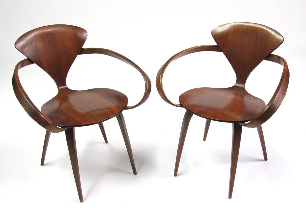 This pair of Arm Chairs were designed by Norman Cherner and manufactured by Plycraft. The walnut veneer has a flowing grain that extenuates the slender lines of this design. Offered as a pair.  This form is both elegant and iconic of the