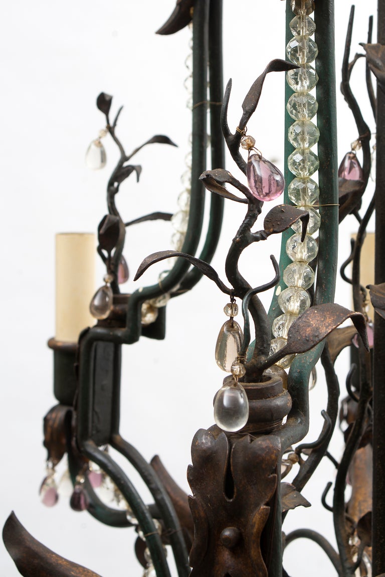 French wrought iron crystal drop eight light chandelier, circa1870.
Adorned with an array of coloured cut crystal pears, grapes, leaves, faceted plaquettes, rosettes and drops. The central support is surrounded by wrought iron vines and glass drops