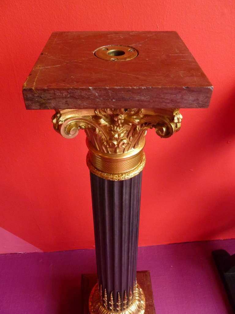 Pair of French bronze and ormolu Corinthian column pedestals. With red marble plinths and platforms (originally revolving) c.1900. 
Supported by a stepped red marble plinth, a foliate ormulu base leads to flamed fillets of bronze leading up the