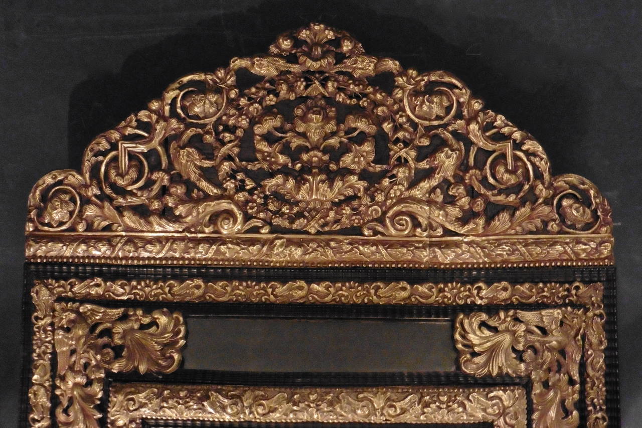 A fine Dutch brass rectangular cushion or 'Repoussé' mirror, circa 1860. The crest richly adorned with birds and floral and foliate ornamentation, the frame with ebonized ripple moulding.
Repoussé is a decorative metal technique which involves