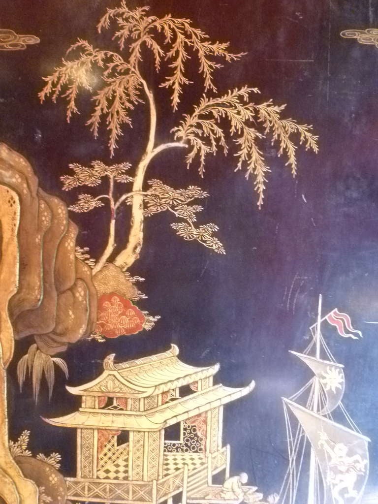 Chinese lacquer panel with riverscape scene c.1900 with later gilt frame. The Romanticised Chinoiserie scene depicted in raised gilt work with a fisherman and boats by a rocky shore with a waterside pagodas. Additional red detailing highlights the