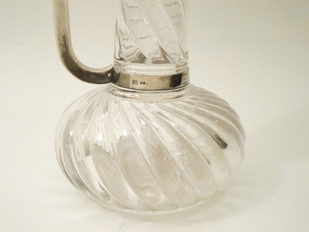 This rare exhibition quality Silver and Crystal Claret Jug was made by Heath and Middleton, and is hallmarked London, 1890. The jug's silver hinged top is a wrythen fan design, and this distinctive design is echoed in the heavy spiral cut neck and