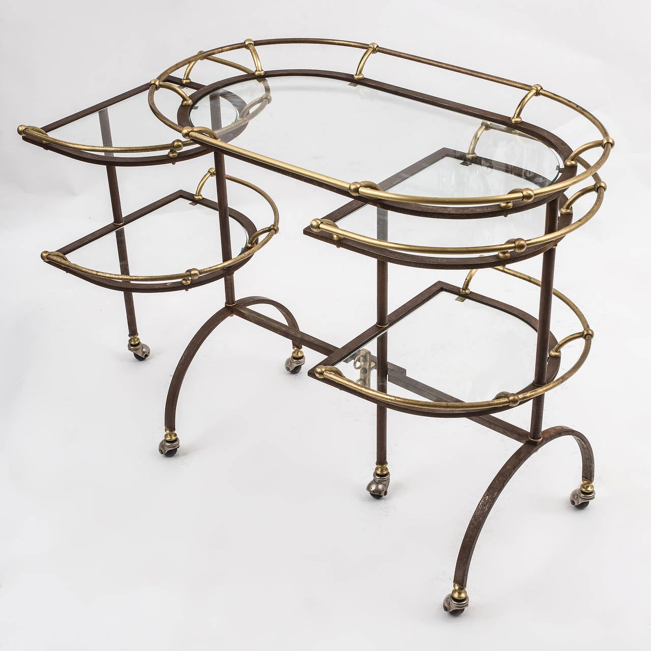 An unusual and incredibly stylish English brass and steel drinks trolley. The curved steel legs with wheels supporting five shelves, four of which swivel outwards, each with a brass gallery, circa 1950. Would suit contemporary or traditional