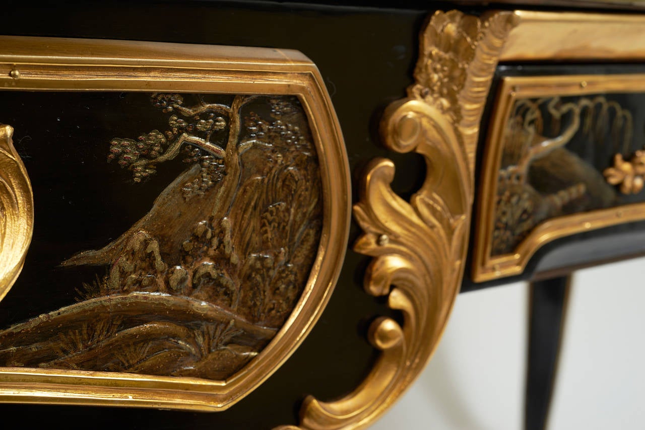 An exquisite French Louis Philippe chinoiserie lacquered bureau plat in the style of Dubois, circa 1860.
Beautifully decorated overall with mountainous chinoiserie landscapes in relief work lacquer, the rectangular red leather-lined top with a