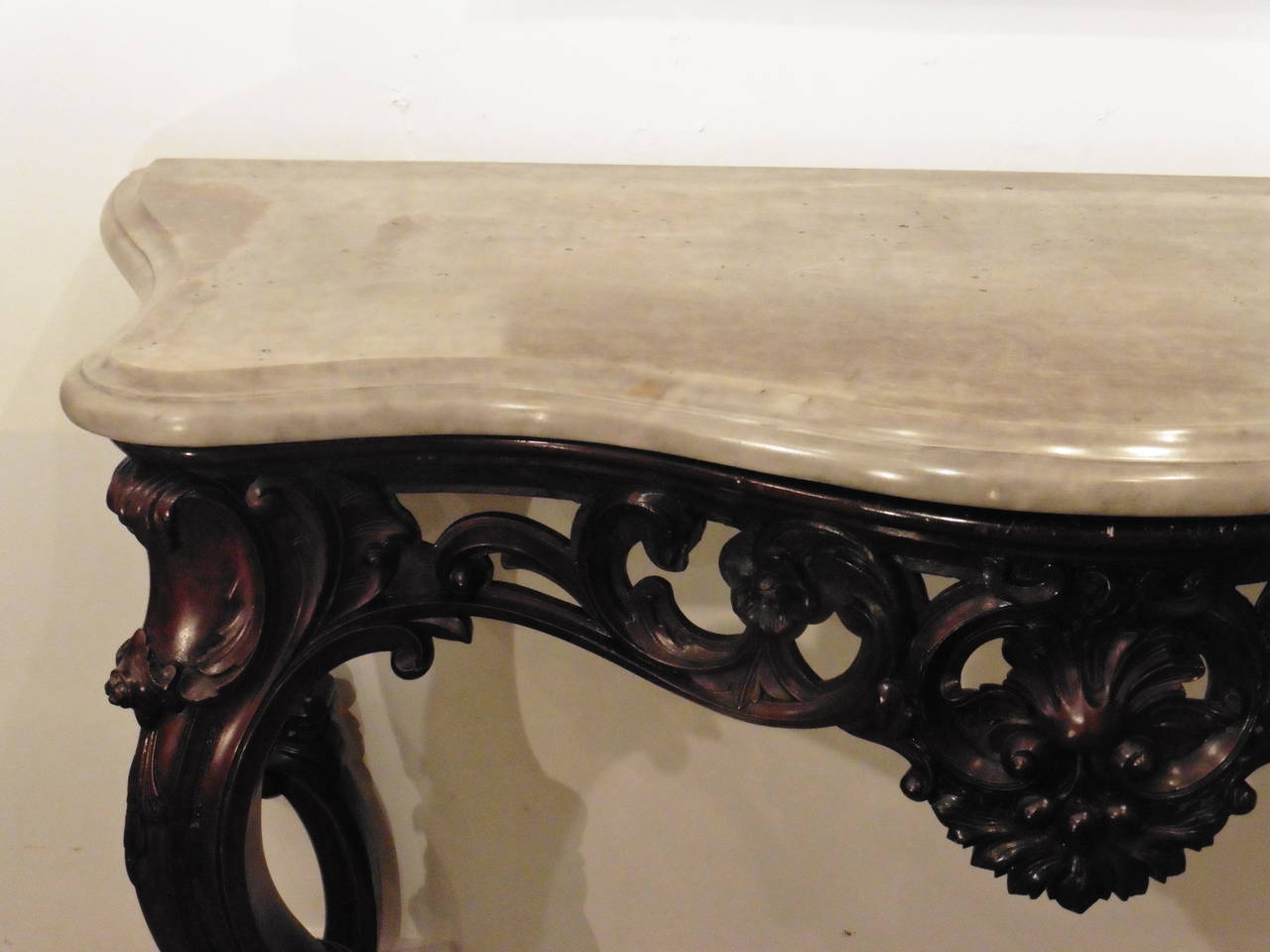 An extremely decorative Anglo-Indian ebonized Rococo style mahogany console table, attributed to Edmonds of Calcutta, circa 1860.
Of serpentine form, with a shaped Italian grey marble top above a pierced frieze wonderfully carved with C-scrolls and