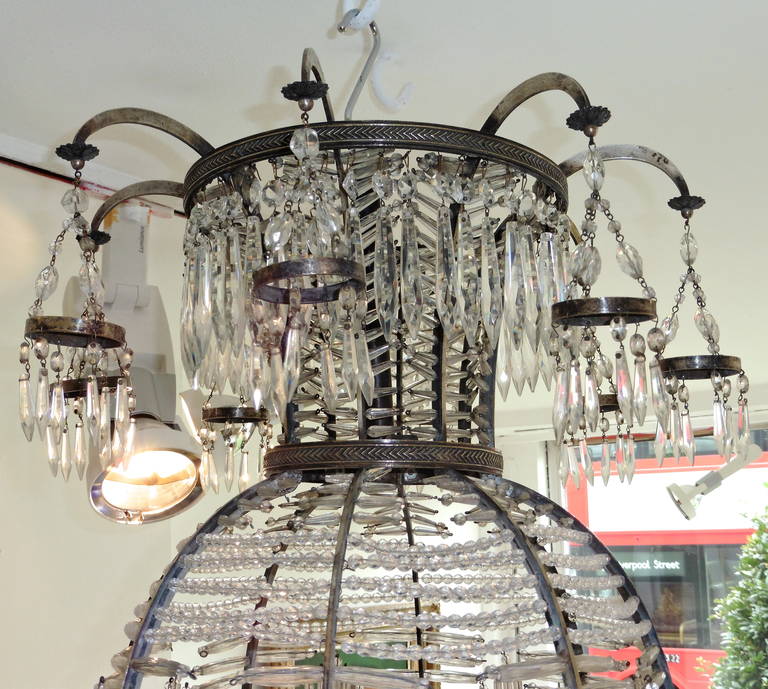 A rare and unusual Baltic silvered bronze and cut crystal neoclassical 'Montgolfier' style eight-light chandelier, circa 1900.
In the shape of a Montgolfier balloon, the top with a profusely adorned corona, the base issuing eight scrolled branches,