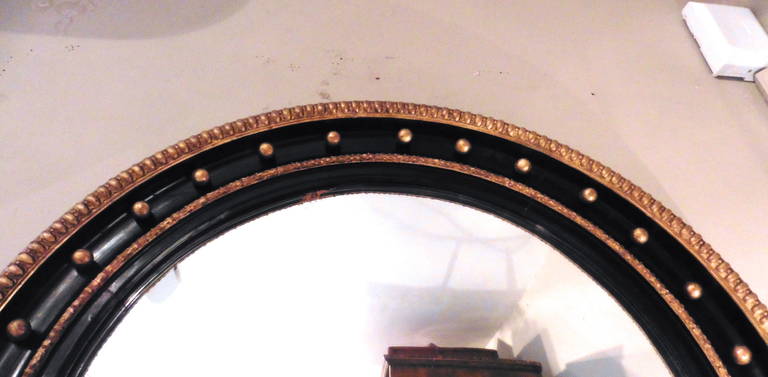 An elegant early Victorian large parcel gilt convex mirror, circa 1850. The ebonized frame decorated with gilt balls and gadrooned moulding.