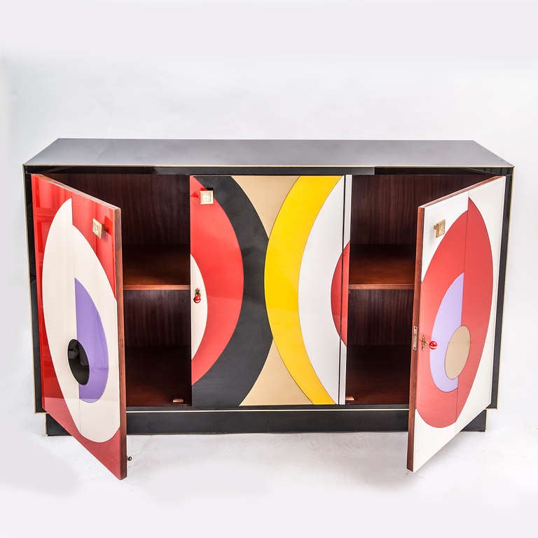 A stunning and extremely unusual Murano glass clad three door sideboard with abstract coloured glass front, after designs by Sonia Delaunay, Italy c.1970.
The solid walnut frame expertly veneered all over with glass panels and beautifully finished