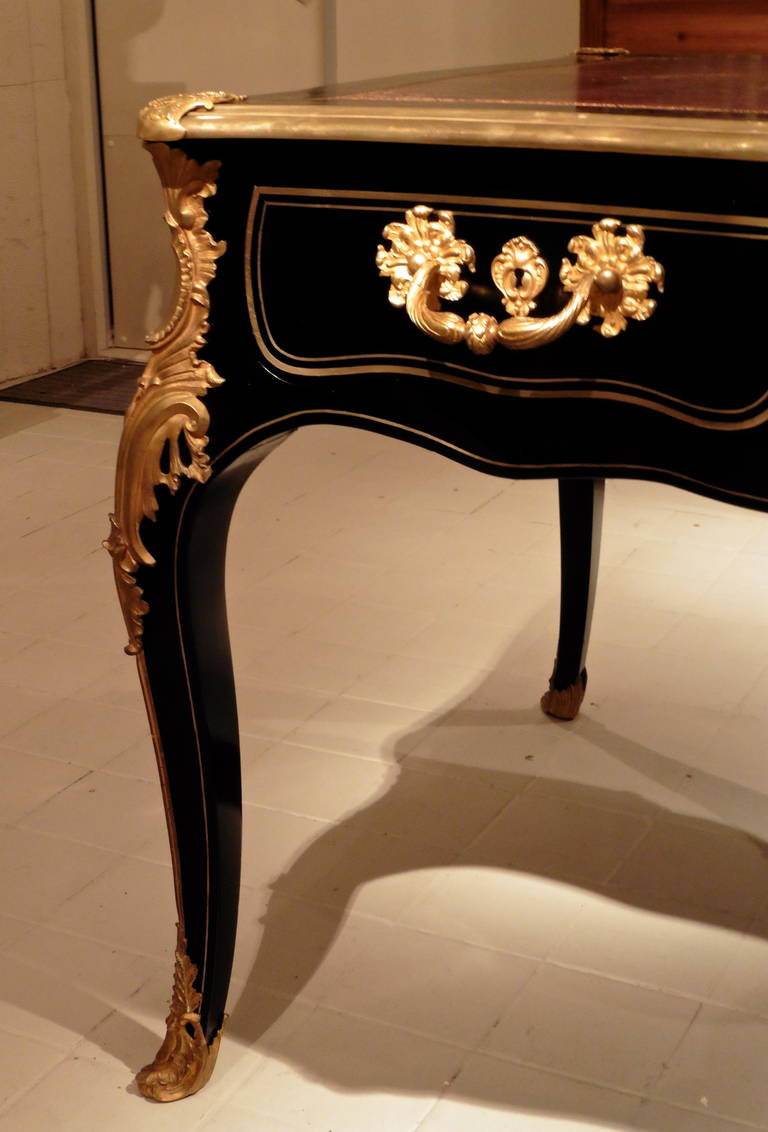 A magnificent French Napoleon III, Louis XV style black lacquered bureau plat, circa 1870.
The shaped top inset with a wonderfully patinated gilt-tooled brown leather writing surface, above a shaped frieze fitted with three drawers, the reverse