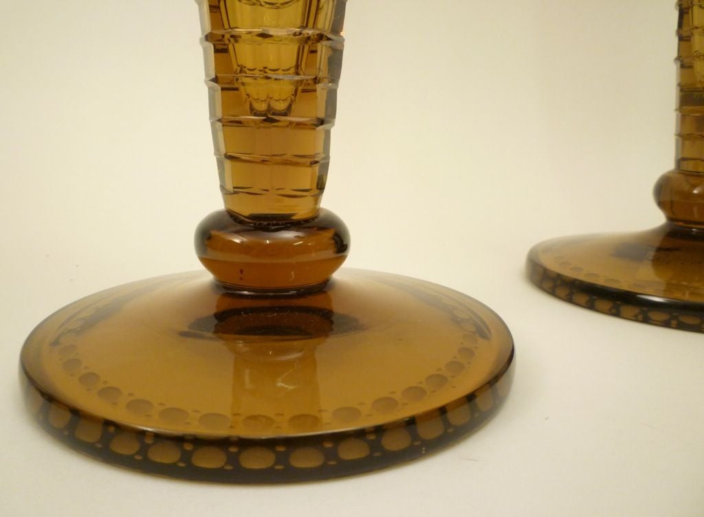 Pair of large amber glass candlesticks with square cut panels and grape and vine engraving. By H.P. Sinclaire and Company of Corning, New York. (Active between 1905 and 1929). Marked with 'S' enclosed by a circular laurel wreath - on underside of