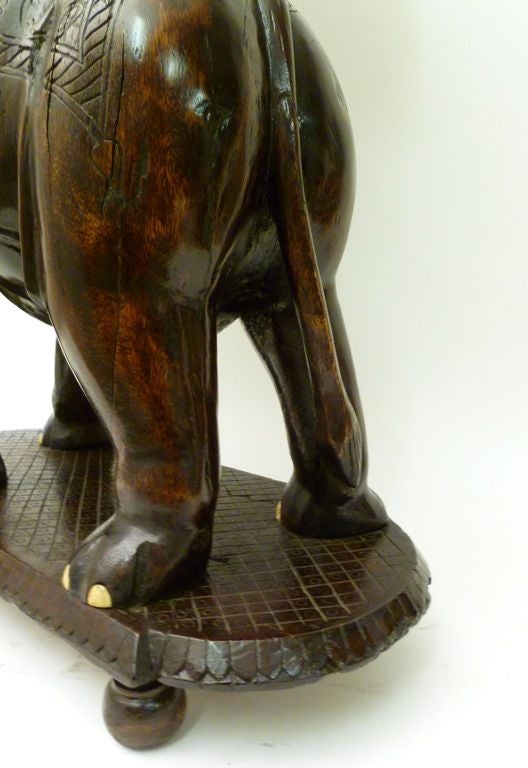 Indian Carved Hardwood Elephant Base Occasional Table, with later faux Ivory toes and tusks.<br />
With a carved circular rosette table top supported in the back of a standing elephant on shaped platform base with geometric carving on turned bun