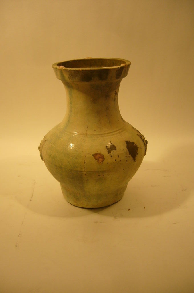 A Chinese Han Dynasty Silver Glaze Pottery 'Hu' Jar with Moulded Tao Mask and Rim Handles and Flaring Neck, with ribbed bands at intervals with across the body, shoulder and rim