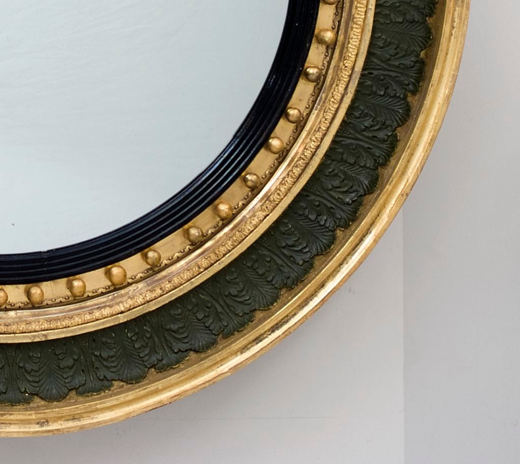 Large Regency parcel gilt convex mirror with original green painted and moulded acanthus decoration.