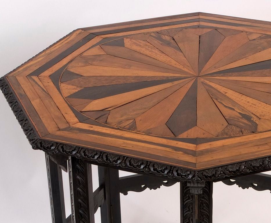 Ceylanese Octagonal Table with Star Shaped Specimen Wood Top on Ebony Base.
The octagonal top with carved edge, inlaid with radiating specimen wood veneers, including palmwood, jackwood, satinwood, ebony and coromandel on a folding octagonal