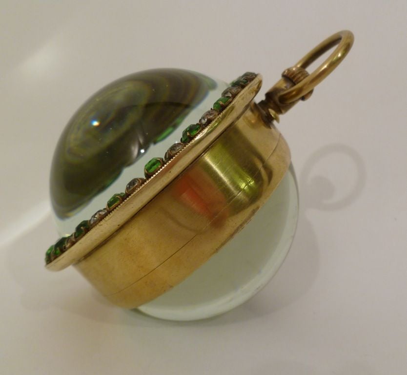 Large glass 'ball' clock/paperweight with brilliant green and clear paste surround, the face painted in floral scenes with gilt details. French movement with second hand subsidiary dial. To the rear, the entire clock mechanism is viewable through